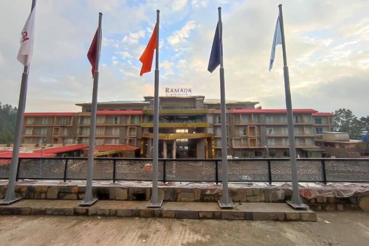 A hotel with a sign reading 'RAMADA' and multiple flags in front.