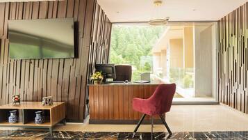 A modern reception area with a wooden panel wall, a flat-screen TV, a desk with a computer, and a red chair.