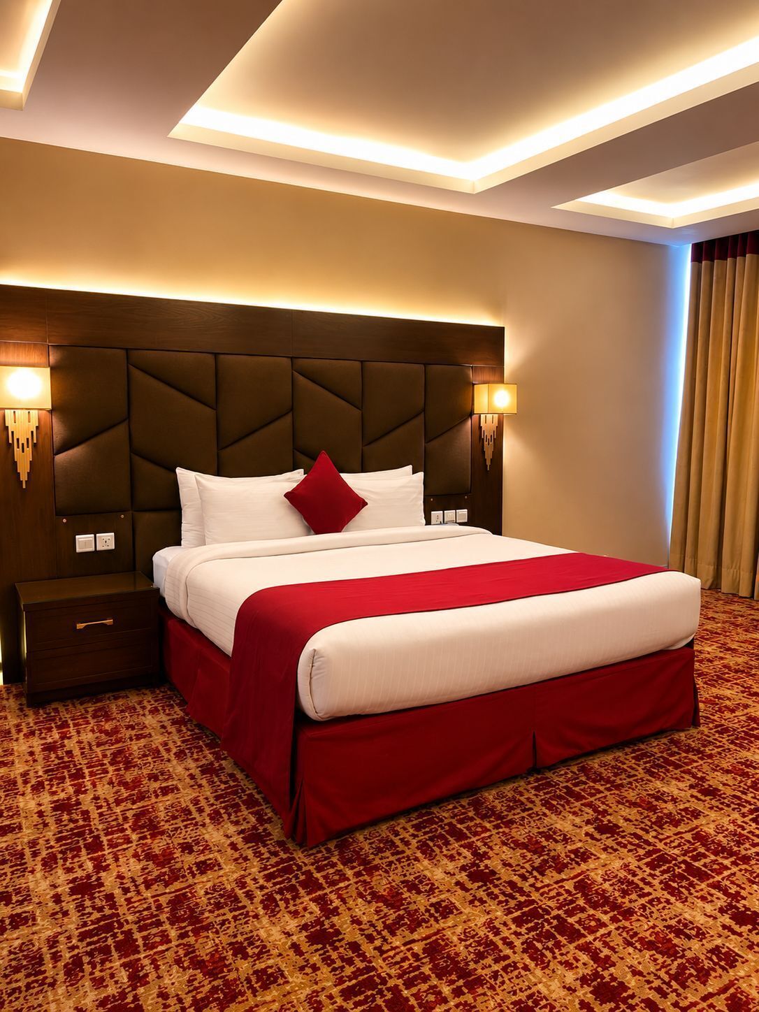 A hotel room with a large bed, a wooden headboard, bedside lamps, and a patterned carpet.