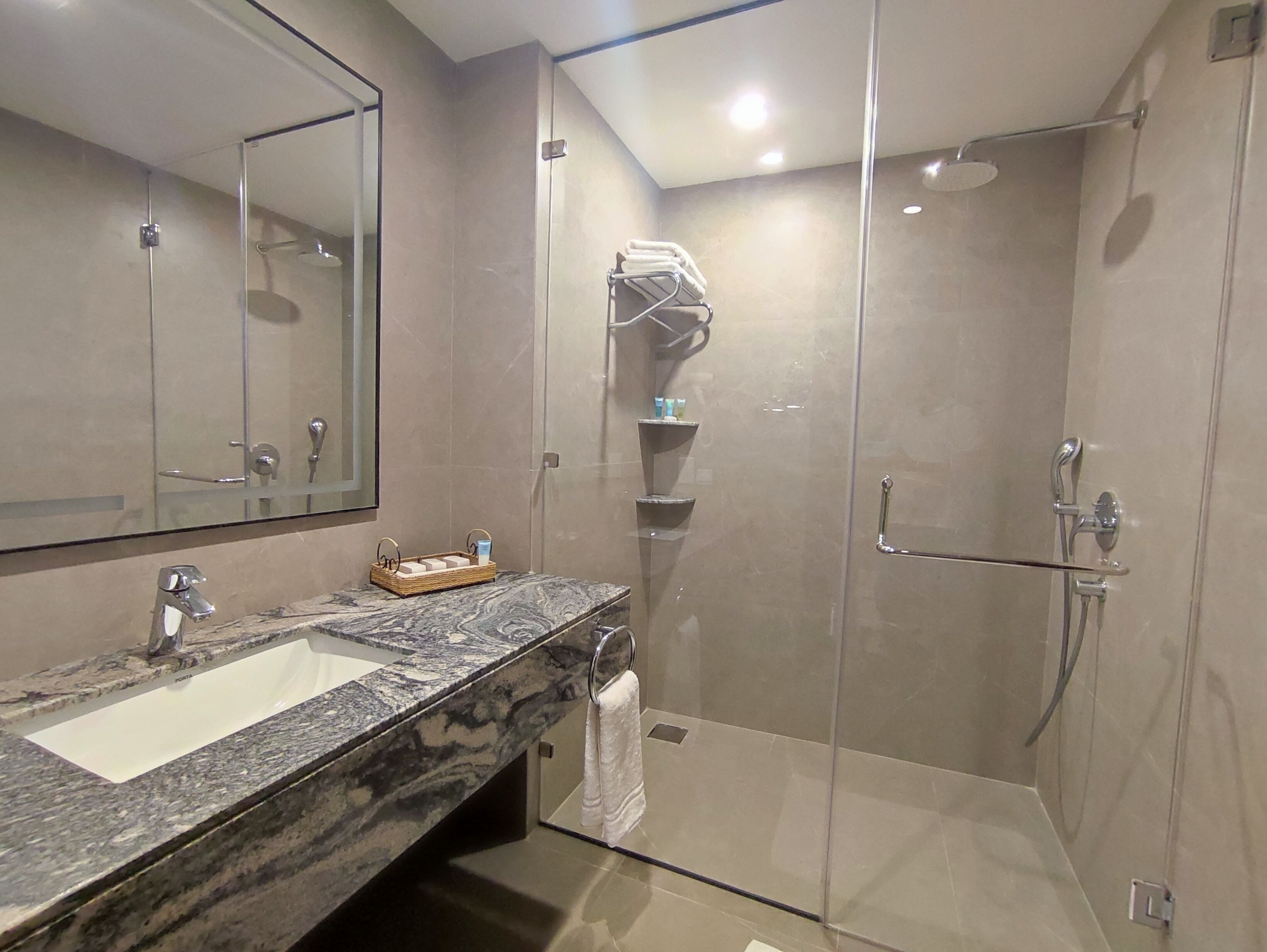 Un baño moderno con lavamanos de mármol, cabina de ducha de vidrio y toallero.