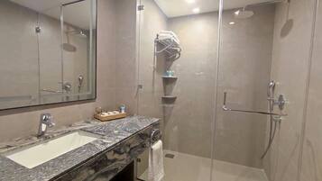 Un baño moderno con lavamanos de mármol, cabina de ducha de vidrio y toallero.