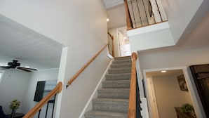 Un escalier avec des rampes en bois et des marches recouvertes de moquette, menant à un niveau supérieur.