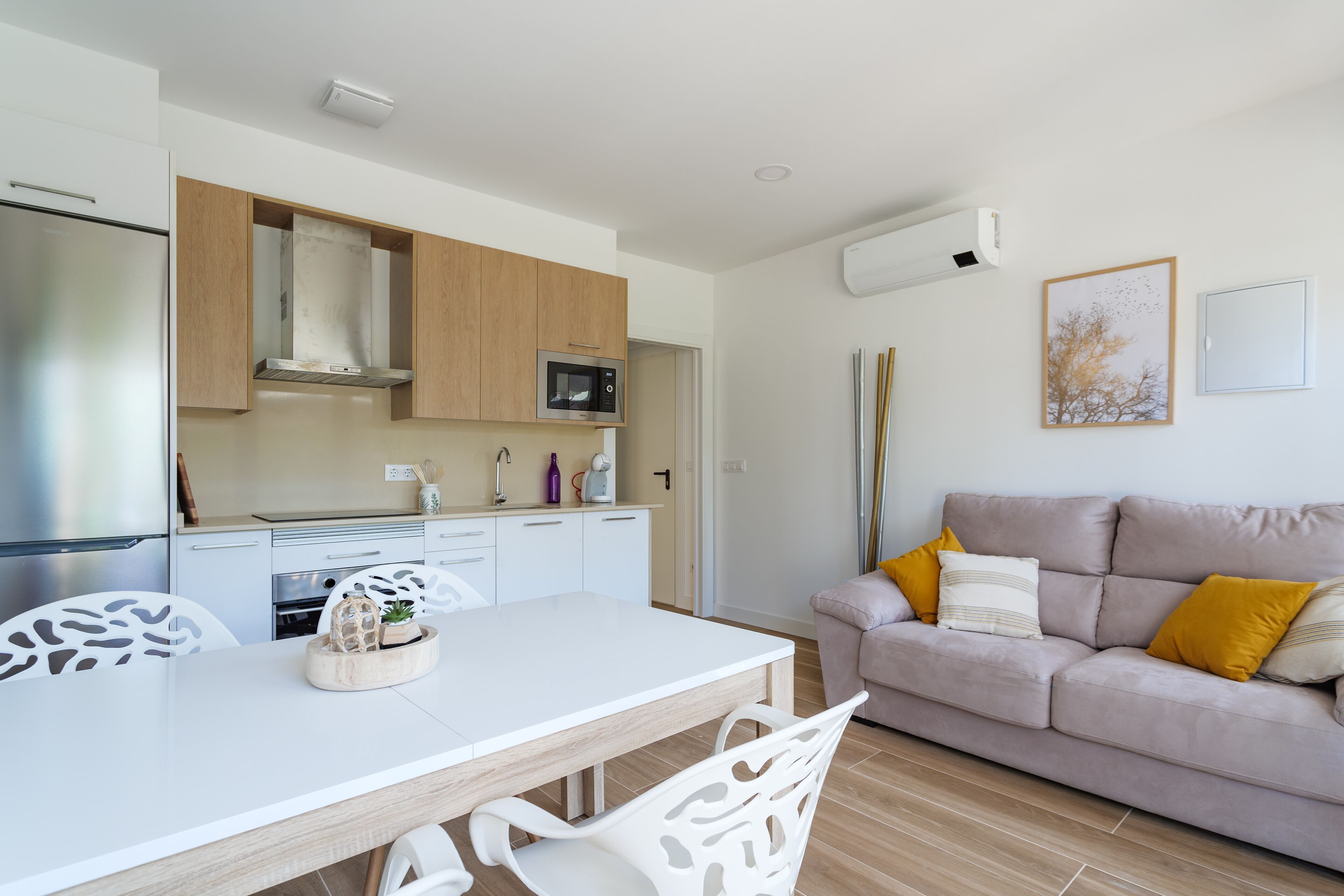 A modern kitchen with white cabinets, a microwave, and a dining area with a white table and chairs.