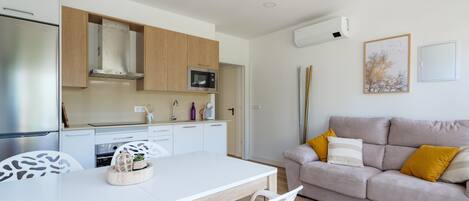 A modern kitchen with white cabinets, a microwave, and a dining area with a white table and chairs.