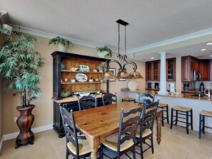 A dining area with a wooden table and chairs, a decorative cabinet with various items, and a hanging light fixture.