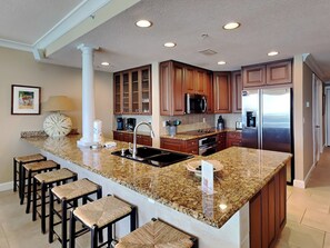 A modern kitchen with granite countertops, stainless steel appliances, and wooden cabinets.