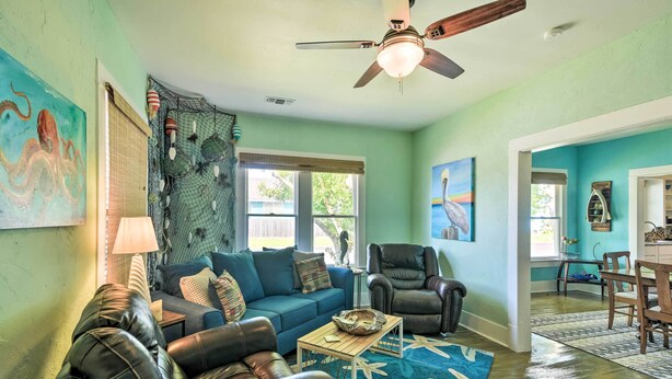 Ein Wohnzimmer mit blauem Sofa, Ledersesseln, einem Holztisch und einem Deckenventilator.