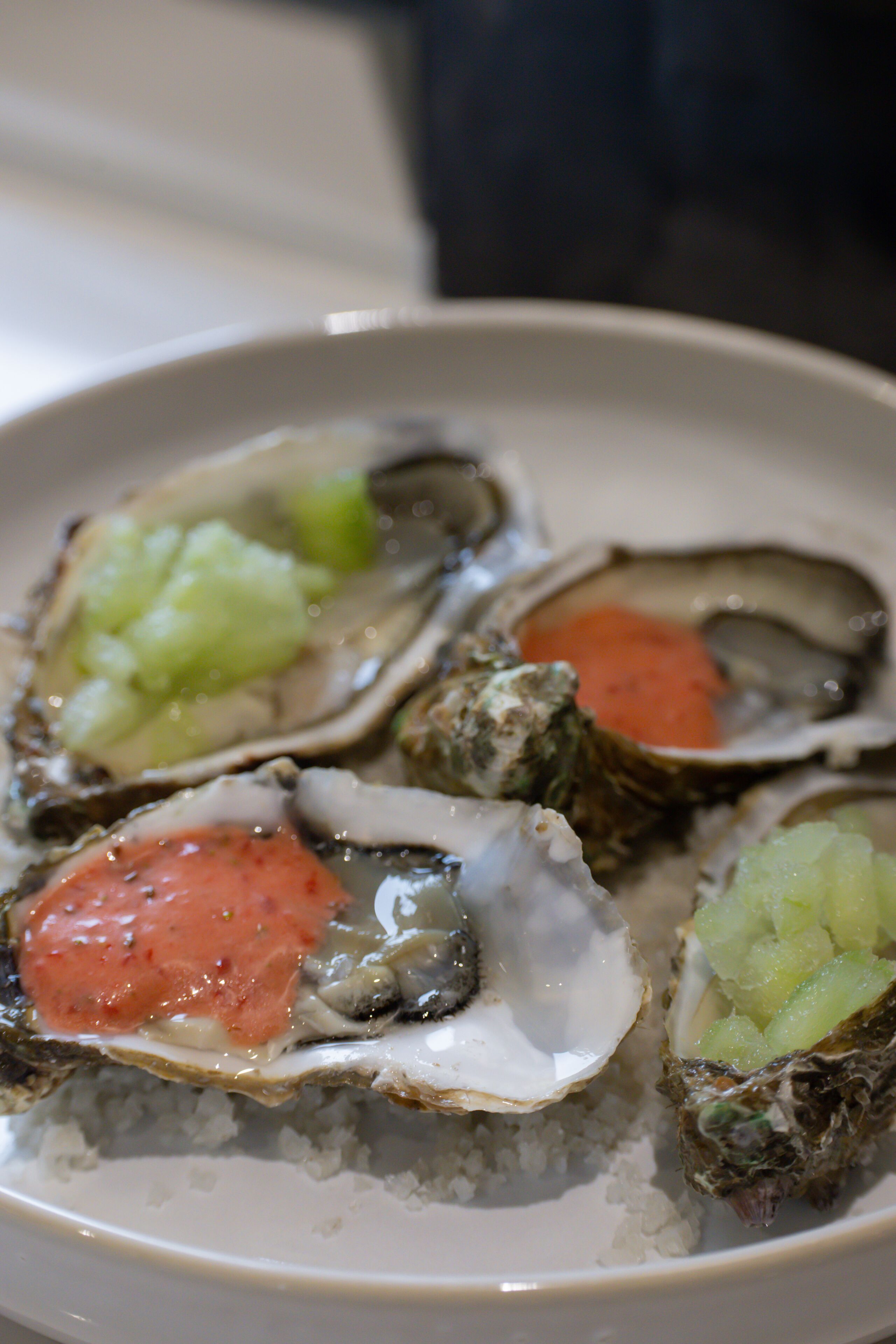 A plate of oysters with different toppings.