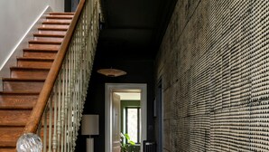 A hallway with a wooden staircase, a patterned wall, and a checkered floor. - Maison Groleau (Mombrier)