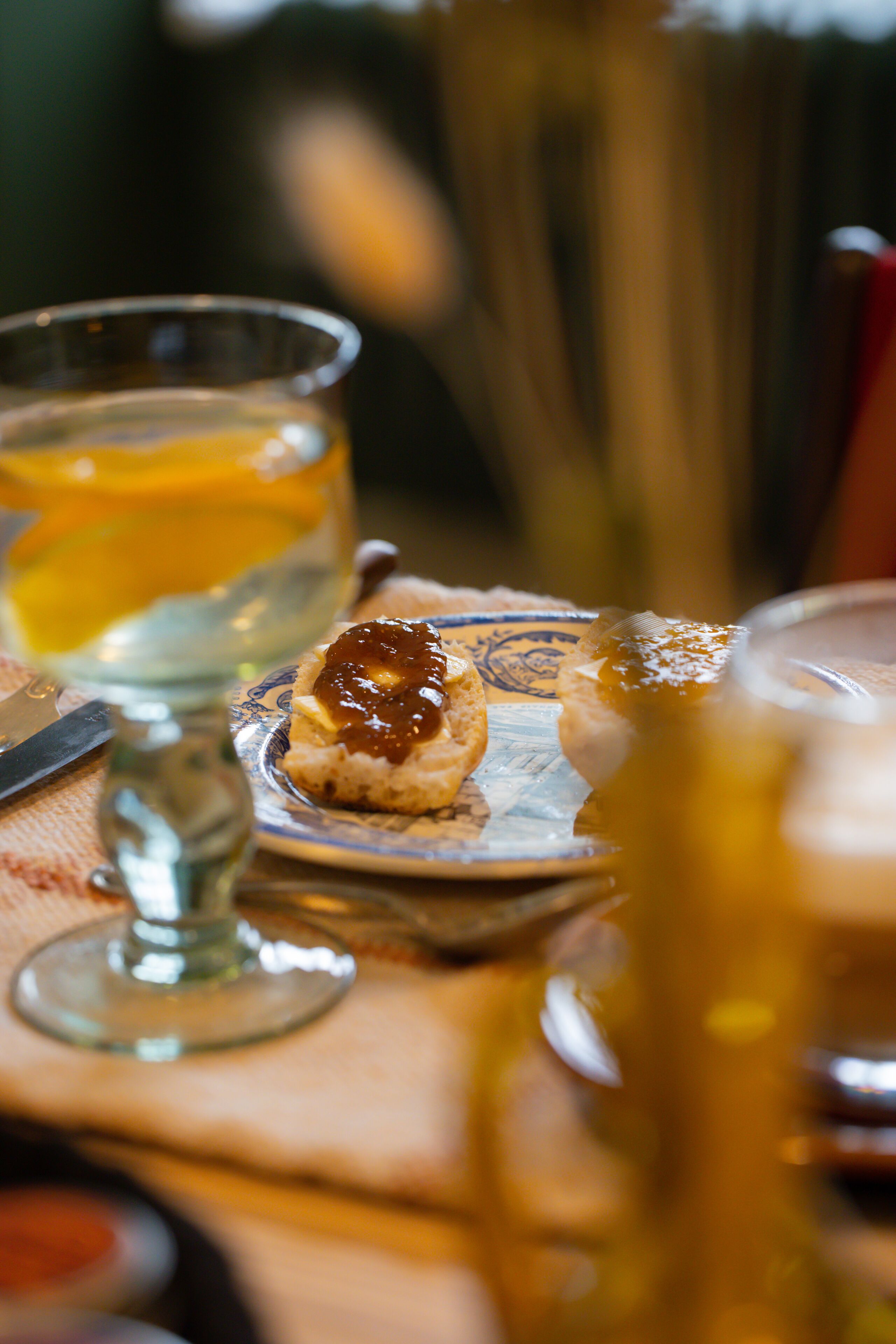 A table with a glass of white wine, a glass of orange juice, and a small plate with a pastry.