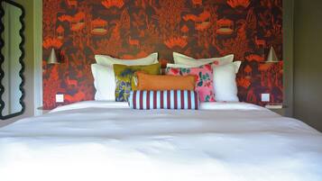 A bed with multiple pillows and a patterned wall behind it.