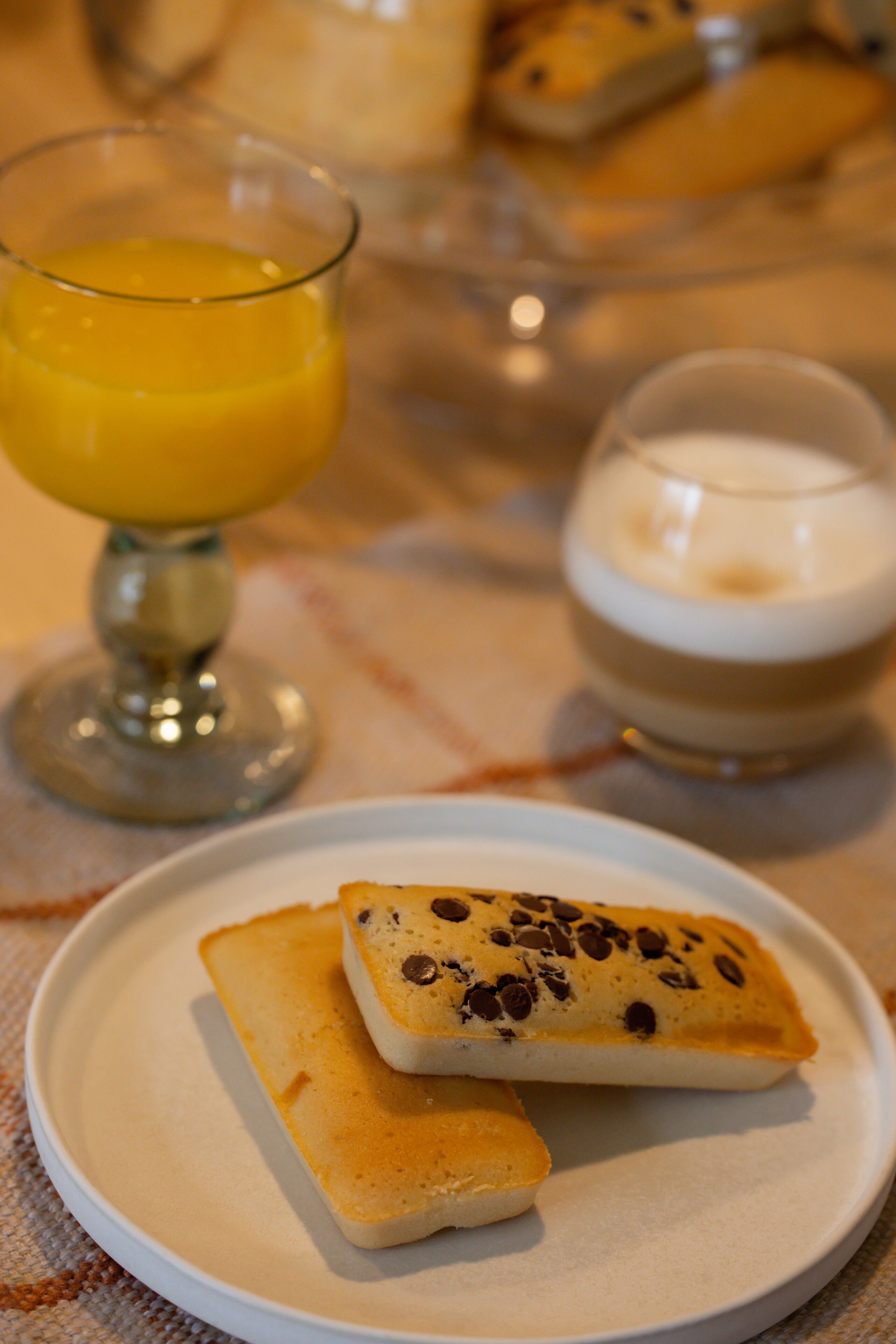 Un plato con un pastel y un vaso de zumo de naranja.