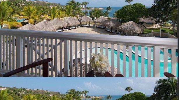 A pool area with a white railing, thatched umbrellas, and a view of the ocean and palm trees. - Luxurious 1 Bedroom Tropical Junior Suite (Dominican Republic)