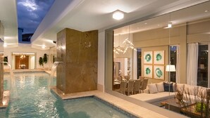 A spacious indoor pool area with a seating area and a dining setup.