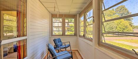 A sunroom with two blue chairs, large windows, and a view of the outside.