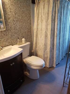 A bathroom with a white toilet, a sink with a mirror, and a shower curtain.