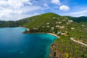 A coastal area with houses on a hillside overlooking a turquoise bay.