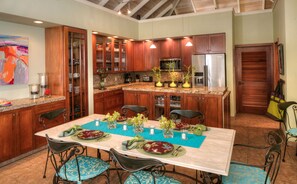 Una cocina moderna con encimeras de granito, armarios de madera y electrodomésticos de acero inoxidable.
