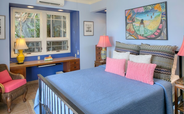 A bedroom with a bed, a desk, a chair, and a window.