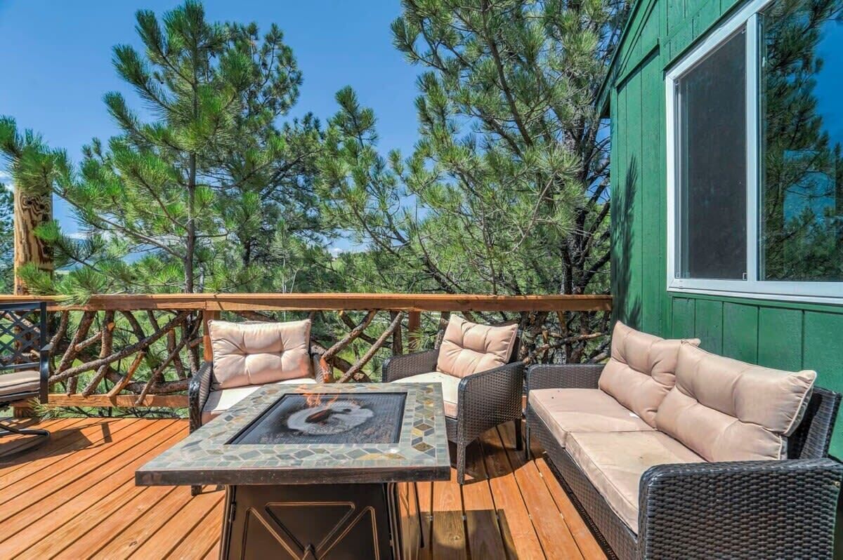 An outdoor deck with a table and chairs, surrounded by trees.
