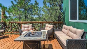 An outdoor deck with a table and chairs, surrounded by trees.