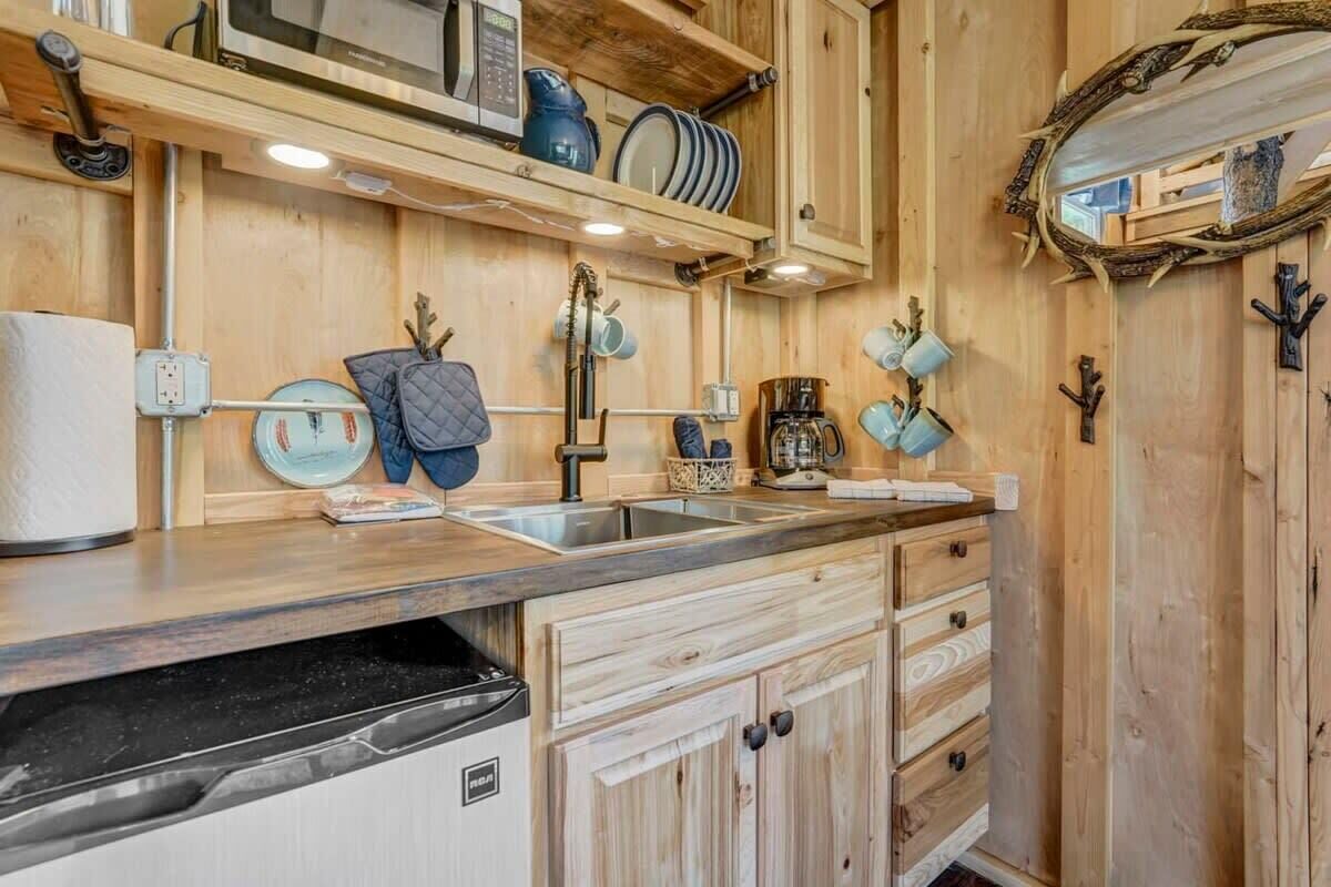 Una cucina in legno con lavastoviglie integrata, una macchina per il caffè e un espositore a parete con stoviglie.