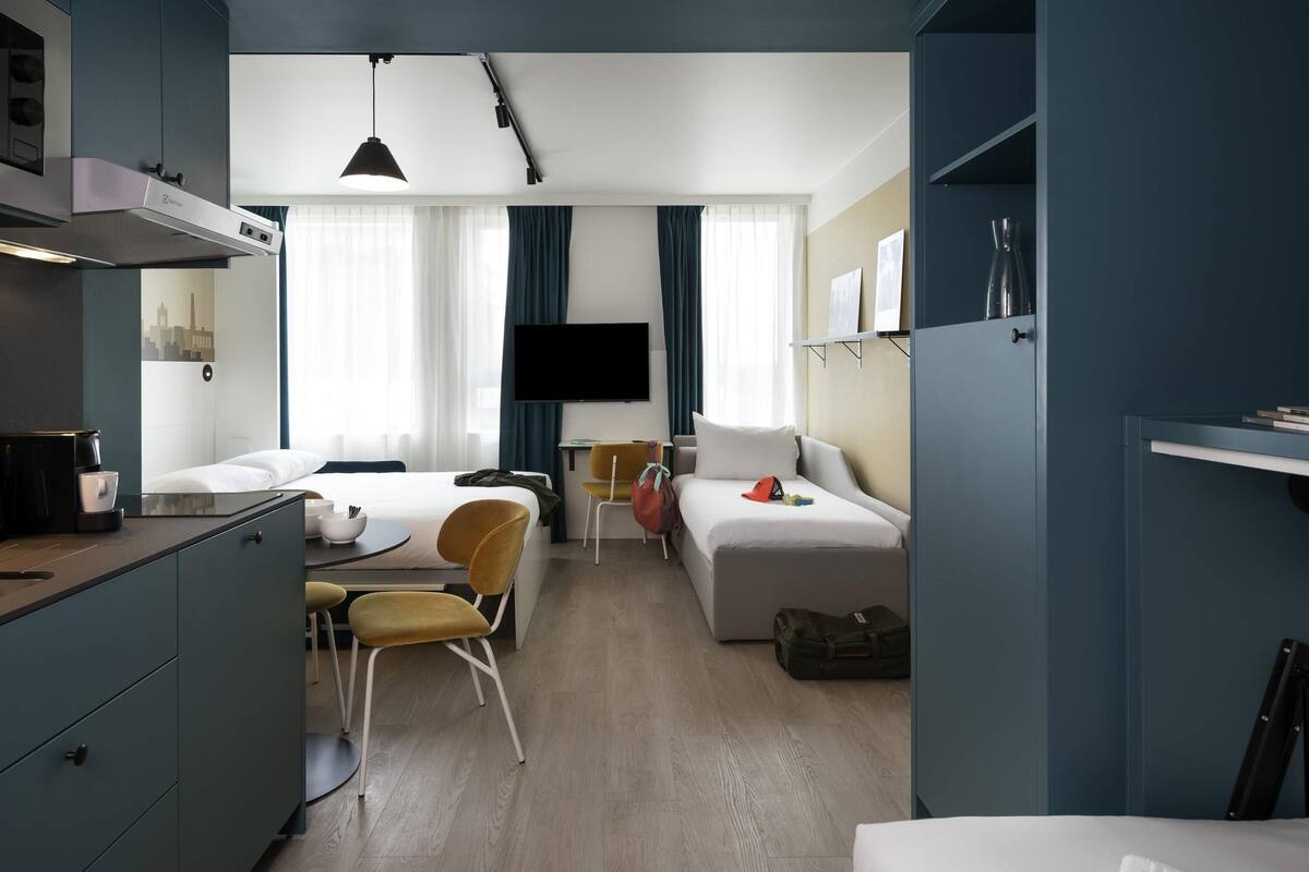 Une chambre d’hôtel compacte comprenant un coin cuisine, un lit, un bureau et un téléviseur.