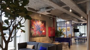 A modern lounge area with a sofa, round tables, a red cabinet, and a ping pong table. - Adagio Access Gent Centrum Dampoort (Ghent)