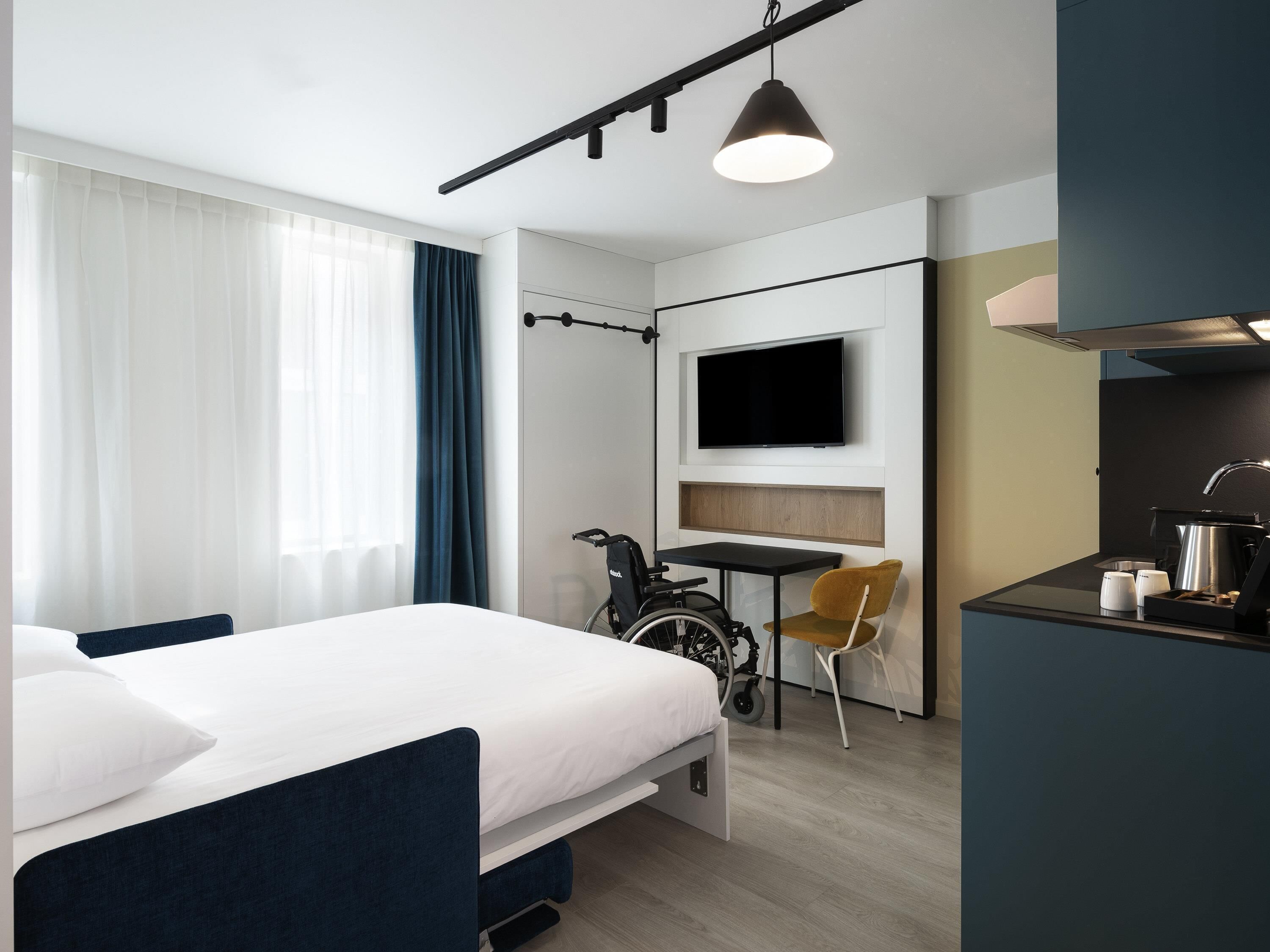 Une chambre d’hôtel moderne équipée d’un lit, d’un bureau, d’une chaise, d’une télévision et d’un vélo.