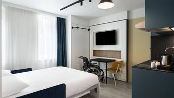 A modern hotel room with a bed, a desk, a chair, a television, and a bicycle.