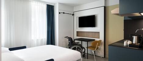 Une chambre d’hôtel moderne équipée d’un lit, d’un bureau, d’une chaise, d’une télévision et d’un vélo.
