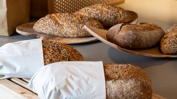 Una vitrina de panadería con diferentes panes y un cuchillo sobre tabla de cortar.