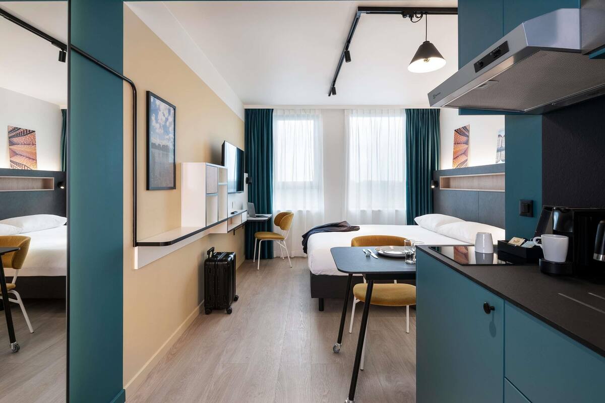 Une chambre d’hôtel équipée d’un lit, d’un bureau, d’une chaise et d’une kitchenette.