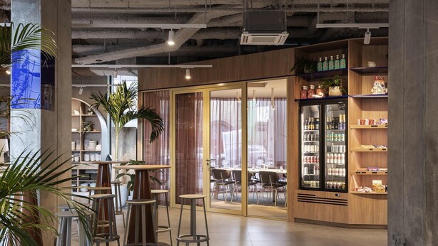 A modern interior with high ceilings, exposed ductwork, and a mix of wooden and metal furniture. - Adagio Access Gent Centrum Dampoort (Ghent)