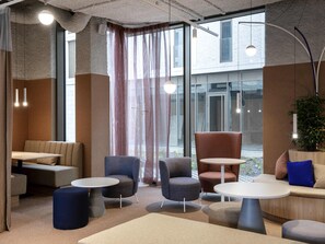 Un intérieur moderne avec des espaces aménagés pour s’asseoir, un mur en verre et une vue sur l’extérieur.