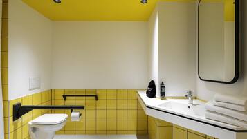 A bathroom with yellow tiles, a white toilet, a sink with a mirror, and a towel rack.