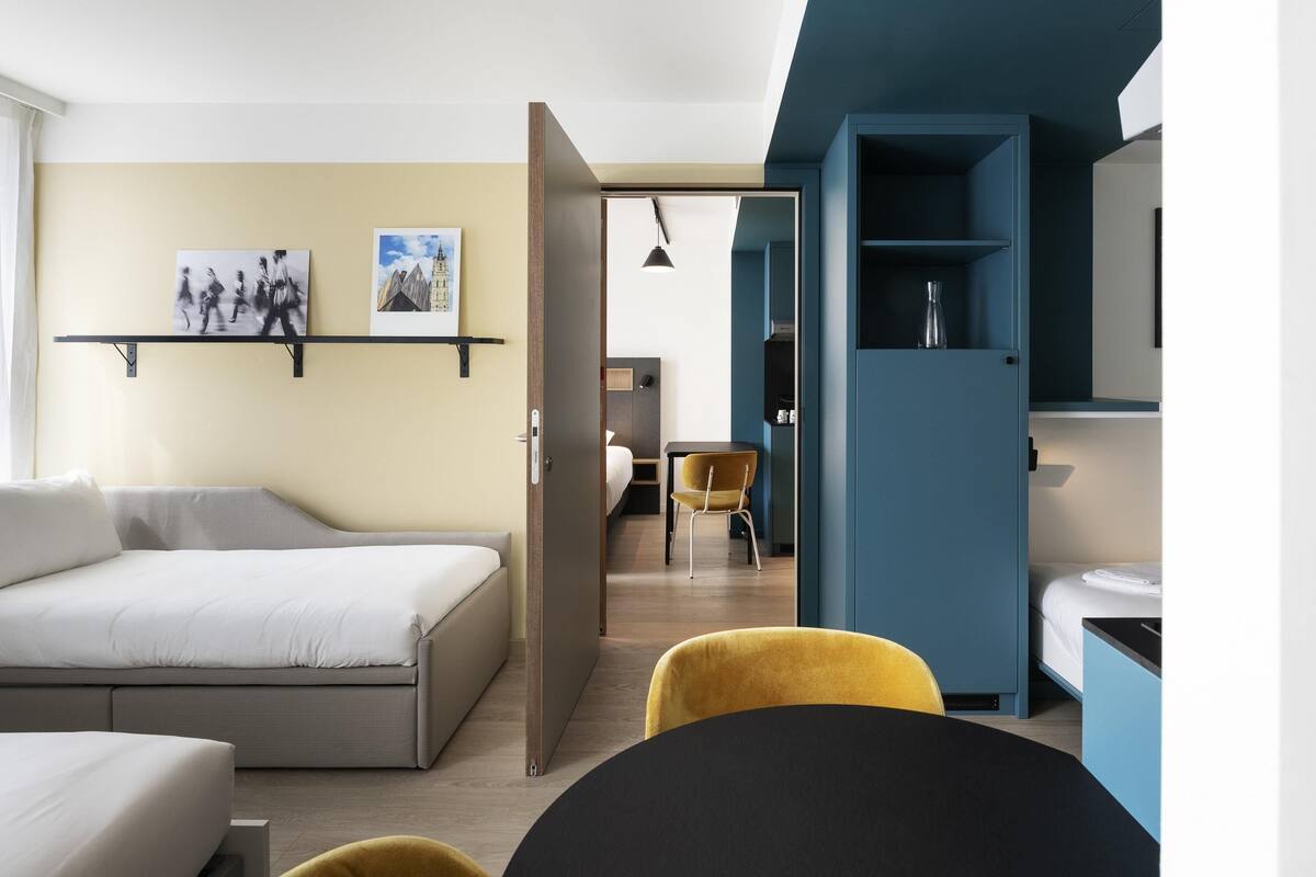 Une chambre d’hôtel moderne équipée d’un lit, d’un bureau, d’une chaise et d’une armoire.