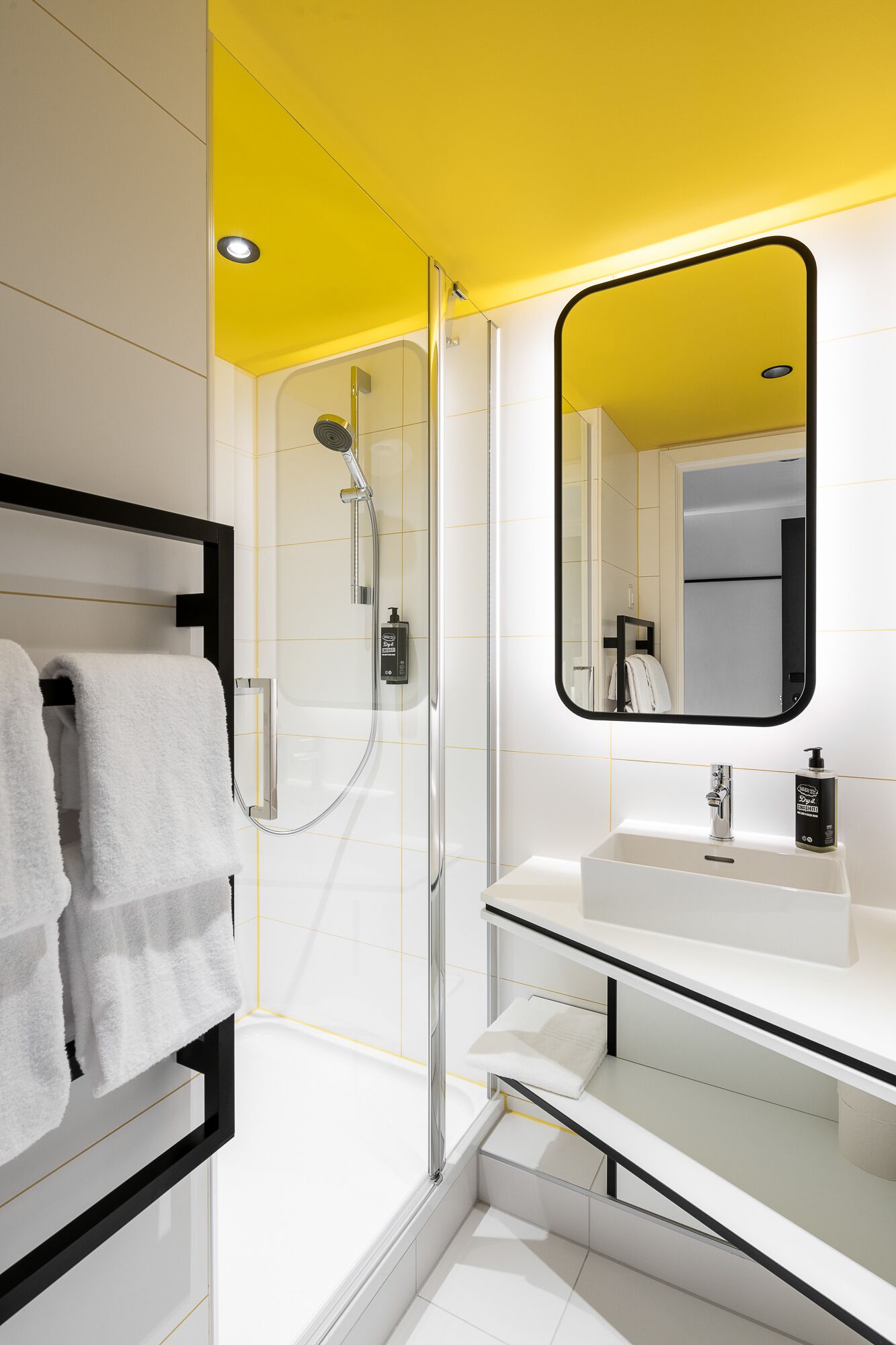 A modern bathroom with a glass-enclosed shower, a white sink, and a large mirror.