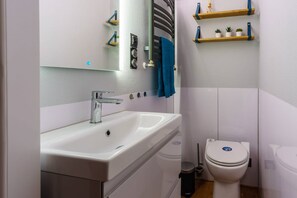 A bathroom with a white sink, a mirror, a towel rack, a toilet, and a trash bin. - "Fjord POLARIS" houseboat with a bio-sauna and rooftop terrace in Barth (Barth)