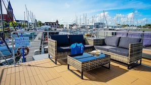 Une terrasse dotée de meubles en osier et d’un panneau indiquant les dimensions maximales autorisées pour les bateaux.