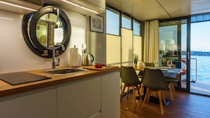 Une cuisine moderne avec un grand miroir rond, un évier en acier inoxydable et un coin repas comprenant une table et des chaises.