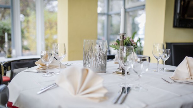 A table set for dining with clear glassware, a decorative vase, and a candle centerpiece. - Gasthaus Mohren (Pfullendorf)