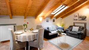Ein gemütlicher Loftraum mit Esstisch, Stühlen, einer Couch und einem Ledersofa.