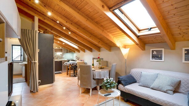 Ein gemütlicher Lofts-Wohnraum mit Essbereich, Küche und hoher Decke mit Oberlichtern.