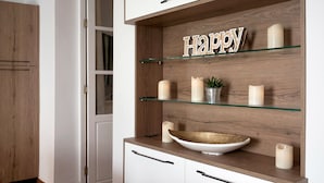 Een keuken met een houten kast, een glazen plank met kaarsen, en een bordje met de tekst 'Happy'.