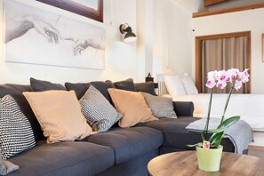 A modern living room with a sofa, pillows, a coffee table, and a potted orchid. - Villa la Luna La Casita – Loft with Shared Pool & Terrace in Vejer, Cádiz (VEJER DE LA FRONTERA)