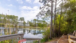 A wooden deck with a warning sign about alligators, a pond, and surrounding trees. - Beachside Villas #413 | Pet-Friendly Condo, Near Beach with Pool (Seagrove Beach)
