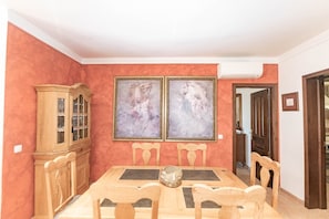 A dining room with a wooden table, chairs, a cabinet, and two framed artworks on the wall.