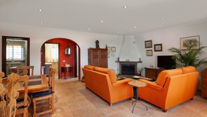 Un salon comprenant un ensemble de canapés, un téléviseur, une cheminée et un coin repas avec des chaises et une table.