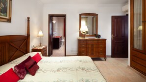 Une chambre à coucher avec un lit, une commode, un miroir et une porte.